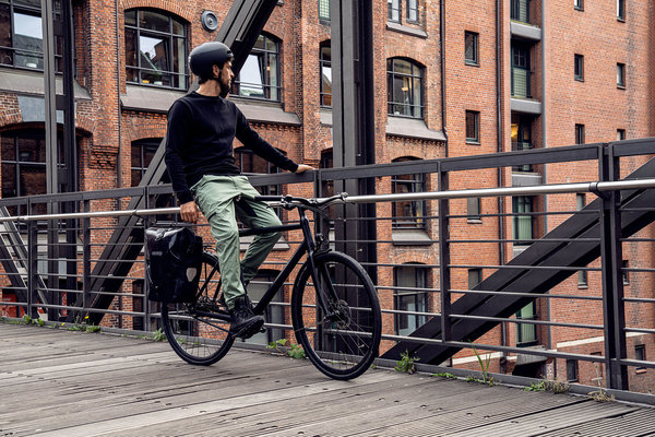 Ein Radfahrer mit seinem Fahrrad und seiner Fahrradtasche auf dem Weg ins Büro.