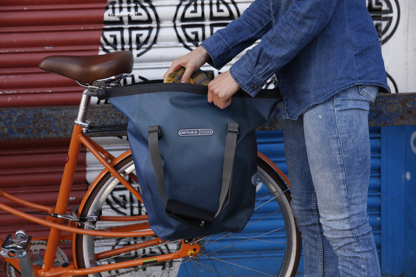 Diese wasserdichte Ortlieb Fahrradtasche befindet sich an einem Fahrradgepäckträger und wird für Einkäufe genutzt.